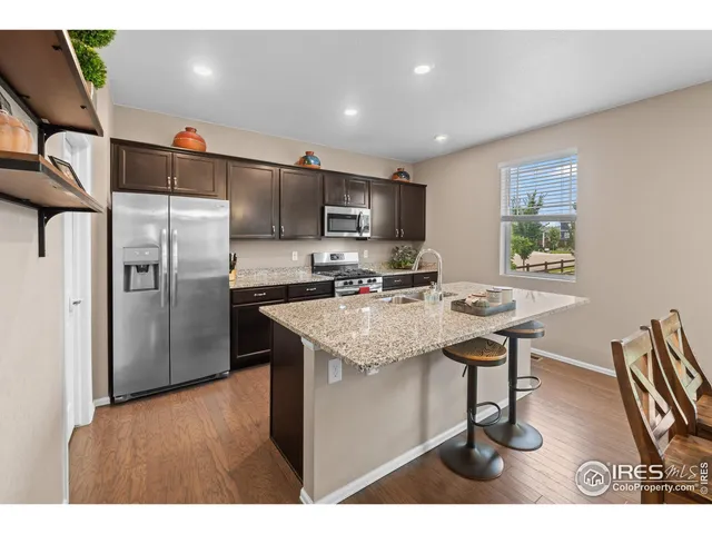 a kitchen with stainless steel appliances kitchen island granite countertop a sink refrigerator and microwave