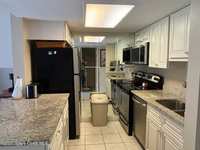 a kitchen with stainless steel appliances a stove a microwave a sink a dining table and chairs