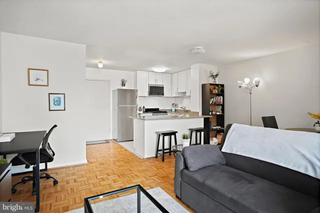 a living room with furniture and a dining table with kitchen appliances
