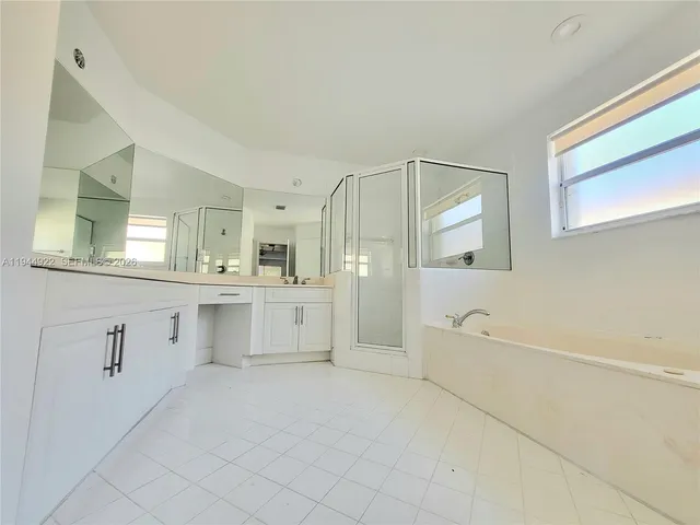 a large white bathroom with a sink mirror and a bathtub