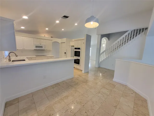 a view of a kitchen with kitchen island a sink stainless steel appliances and cabinets