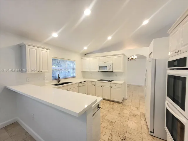 a kitchen with stainless steel appliances a sink a stove a refrigerator cabinets and a counter top space