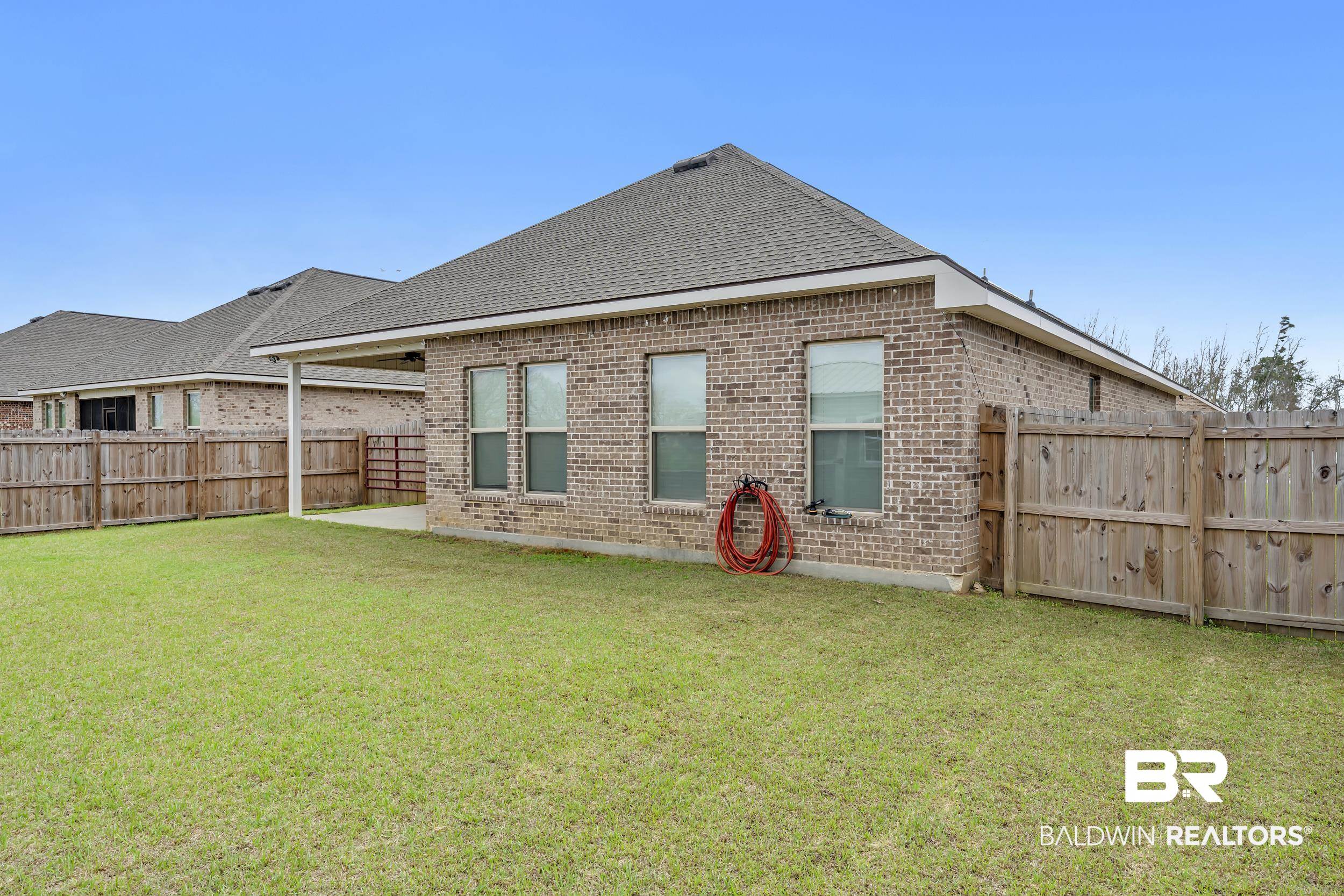 1176 Stella Road Foley, AL 36535 - Photo 34 of 40 Back of property with brick siding, a fenced backyard, a patio area, and a shingled roof