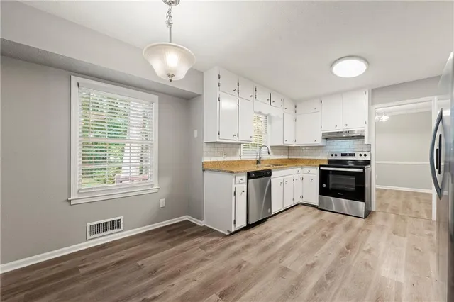a kitchen with granite countertop a refrigerator and a stove top oven
