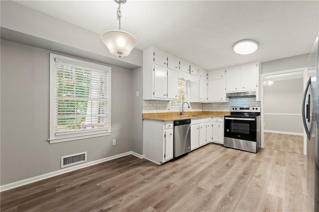 215 Hauteur Place Southwest Lilburn, GA 30047 - Photo 4 of 12 a kitchen with granite countertop a refrigerator and a stove top oven