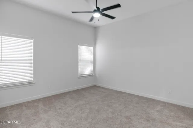 an empty room with a window and ceiling fan