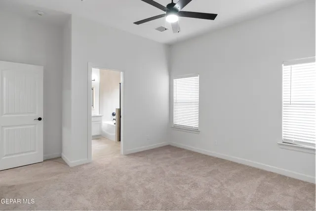 an empty room with windows and fan