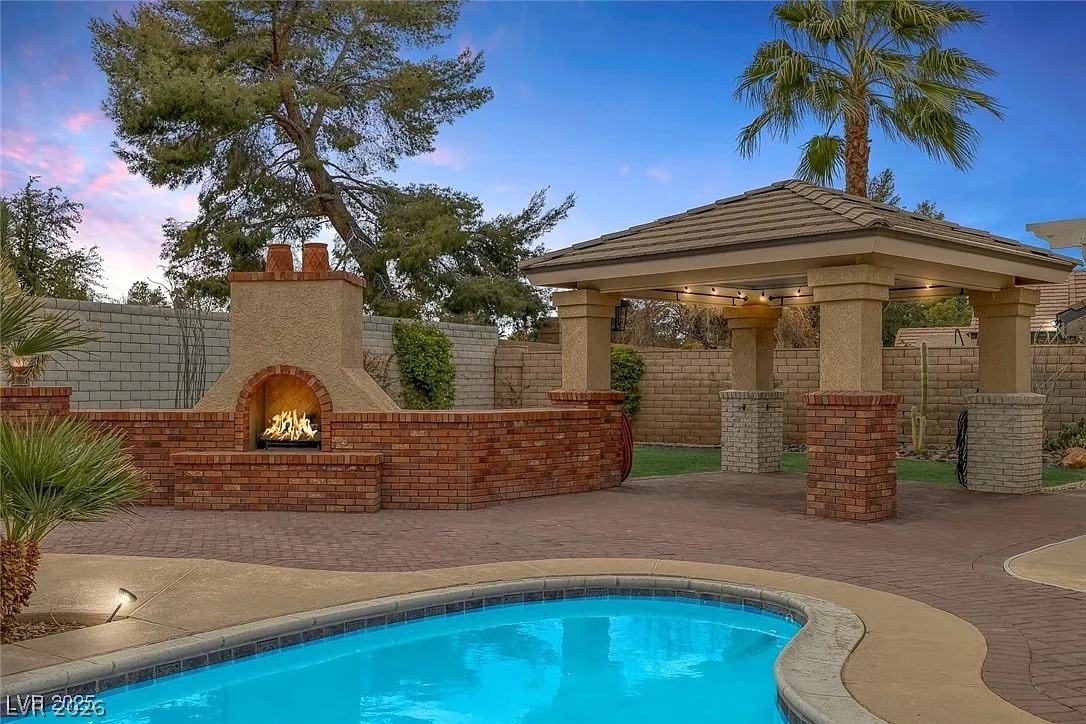 9 Quail Run Road Henderson, NV 89014 - Photo 44 of 57 A private outdoor space with a sparkling pool and a charming fireplace for evening relaxation.