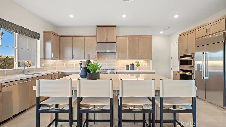 a kitchen with stainless steel appliances kitchen island granite countertop a table chairs microwave and white cabinets