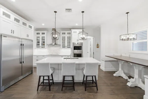 a kitchen with stainless steel appliances kitchen island granite countertop a table chairs and a wooden floors
