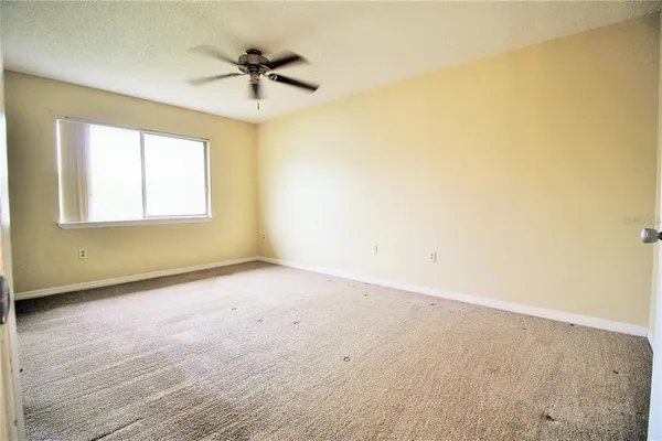an empty room with a ceiling fan and window