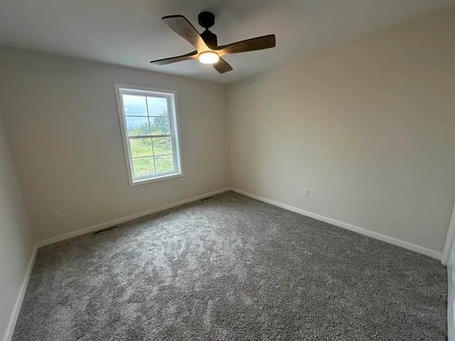 an empty room with a window and ceiling fan