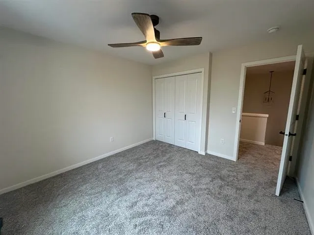 an empty room with closet and a ceiling fan