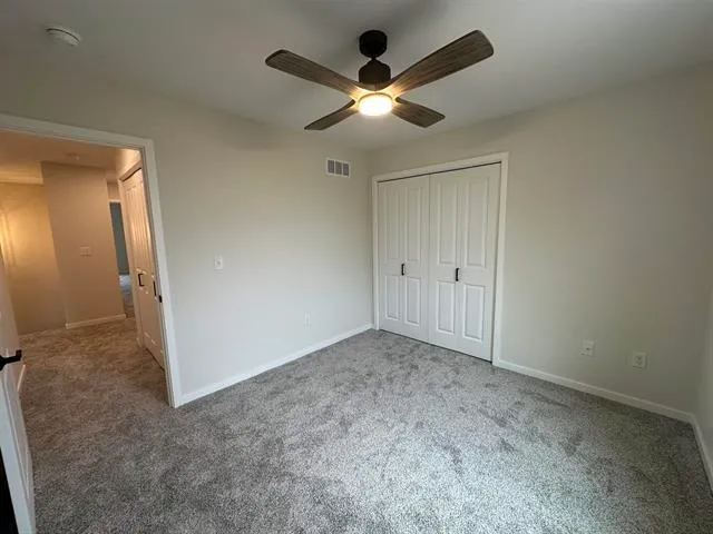 an empty room with closet and a ceiling fan