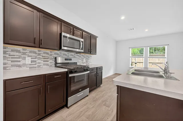a kitchen with stainless steel appliances granite countertop a sink stove and microwave