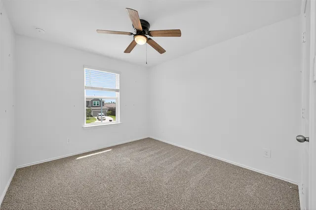 an empty room with a window and a ceiling fan