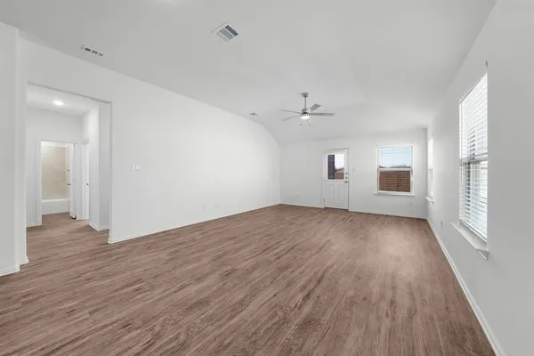 an empty room with wooden floor and windows