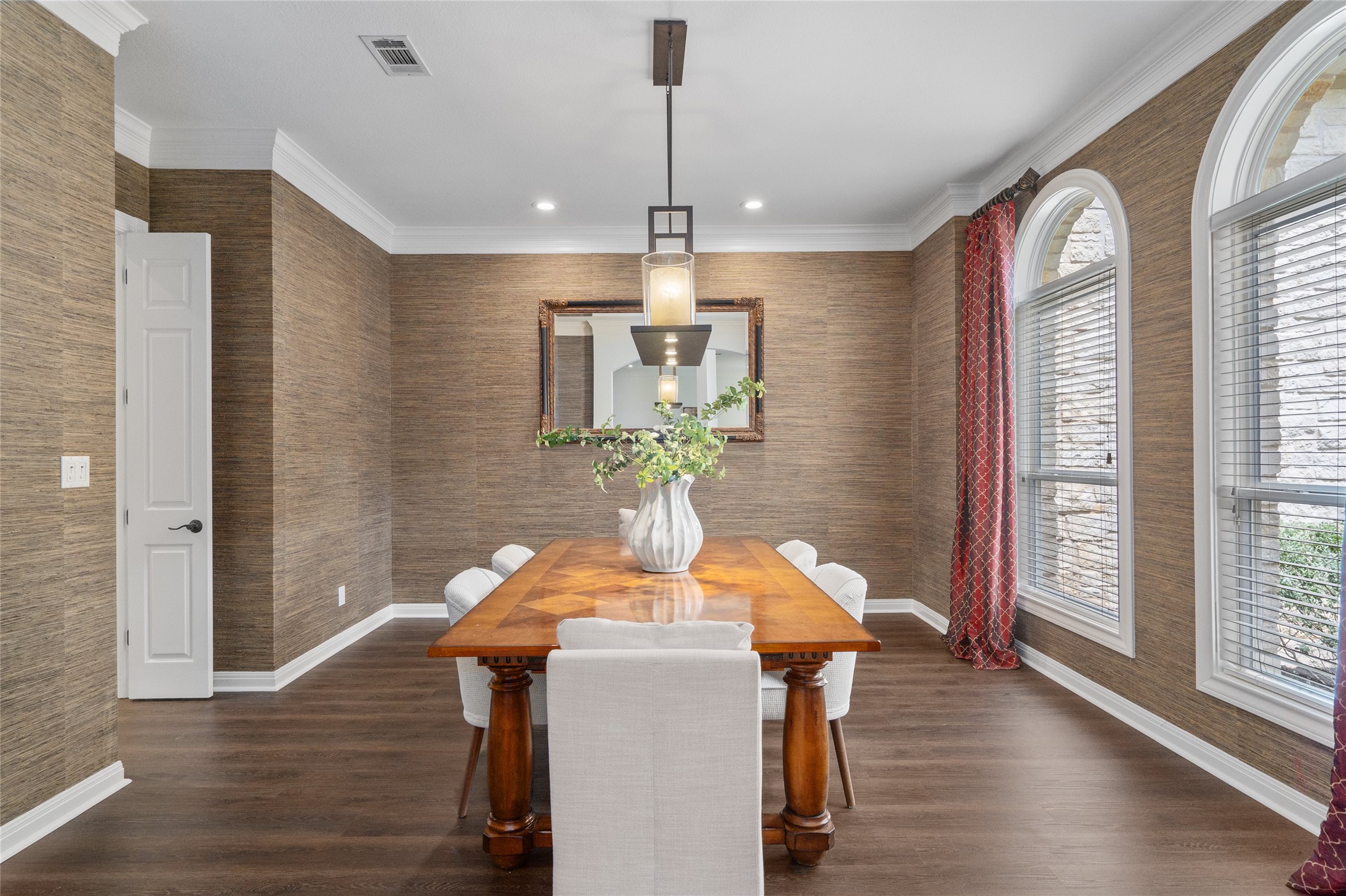 4313 Rio Robles Drive Austin, TX 78746 - Photo 6 of 40 Elegant crown molding complements dark hardwood flooring in this sophisticated dining room, featuring arched windows and a striking overhead light fixture.