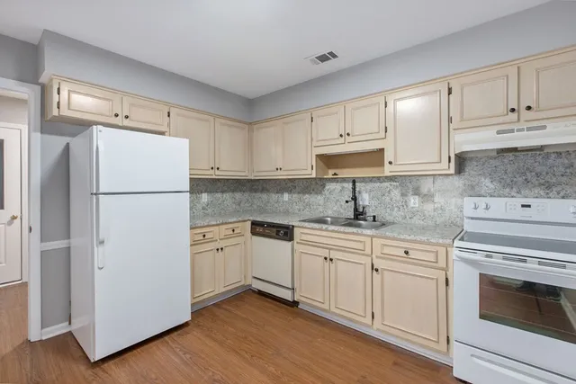 a kitchen with cabinets appliances wooden floor and a window