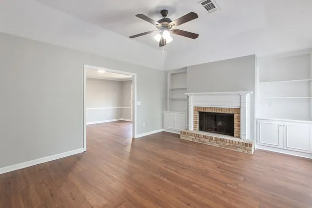 a view of an empty room with a fireplace and a window