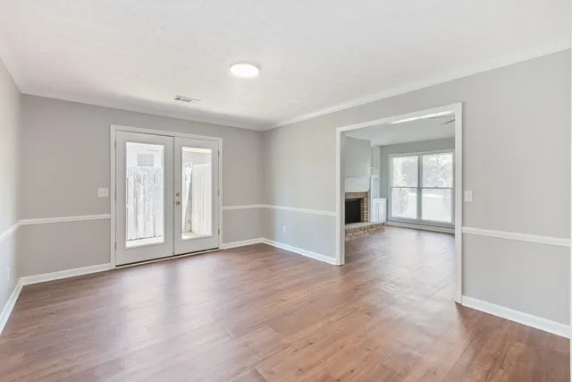 an empty room with wooden floor and windows