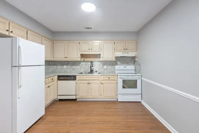 a kitchen with granite countertop white cabinets and white appliances