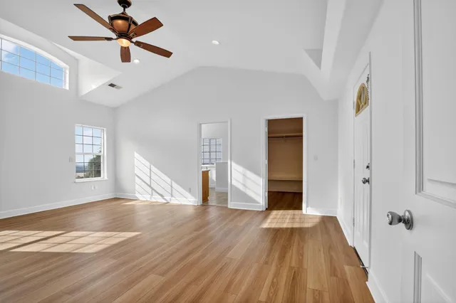a view of a livingroom with wooden floor a ceiling fan and windows