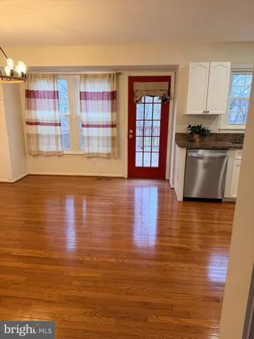 a view of kitchen with stainless steel appliances wooden floor and large window