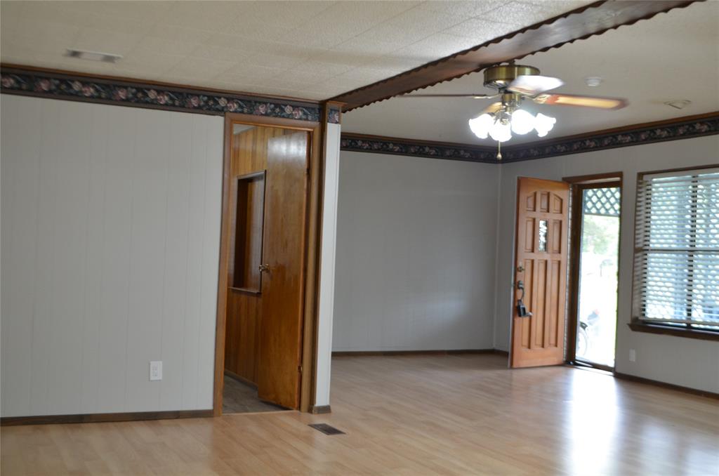2020 Gage Road Cleburne, TX 76031 - Photo 7 of 12 Spacious interior featuring wood-finish flooring, a decorative wood-paneled entry door, and a multi-light ceiling fan