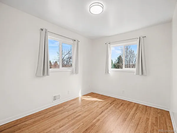 a view of empty room with wooden floor and fan
