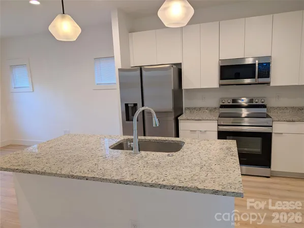 a kitchen with granite countertop a sink stainless steel appliances and cabinets