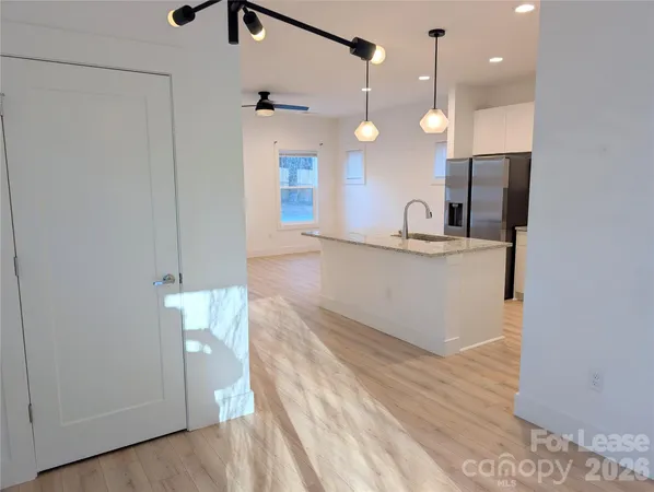 a view of a kitchen with a sink and dishwasher a refrigerator with wooden floor