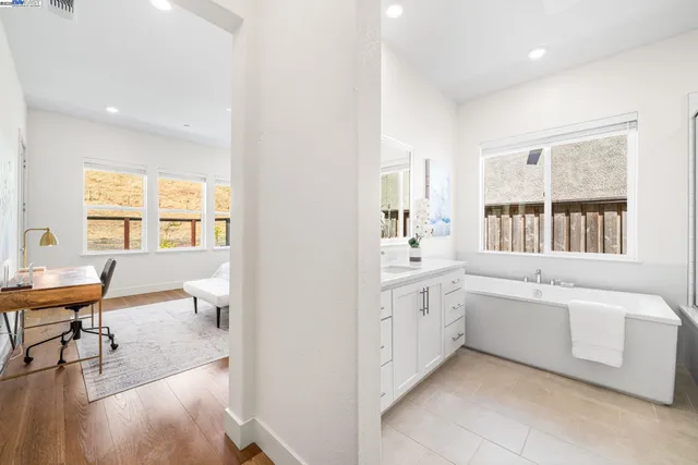 a en suite bathroom with a granite countertop tub next to a window