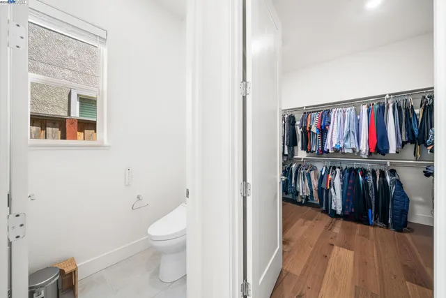 a view of a hallway with wooden floor and a bathroom