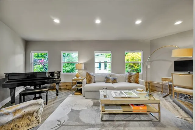 a kitchen with stainless steel appliances kitchen island granite countertop a refrigerator a stove a sink a dining table and chairs with wooden floor