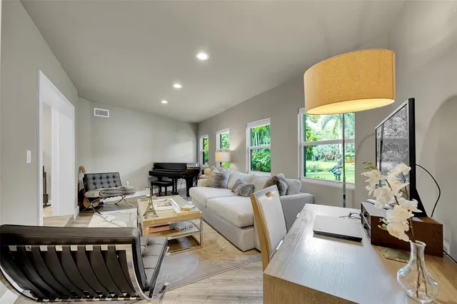 a kitchen with stainless steel appliances a stove a refrigerator a sink a dining table and chairs with wooden floor