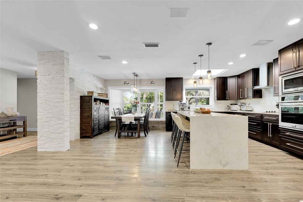 5351 Godfrey Road Parkland, FL 33067 - Photo 18 of 100 a kitchen with stainless steel appliances kitchen island granite countertop a refrigerator a stove a sink a dining table and chairs with wooden floor
