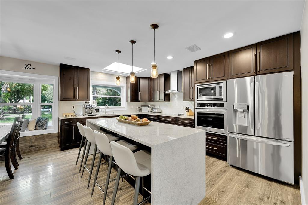 5351 Godfrey Road Parkland, FL 33067 - Photo 20 of 100 a kitchen with stainless steel appliances a stove a refrigerator a sink a dining table and chairs with wooden floor