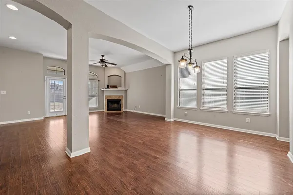 a view of a room with wooden floor fireplace and windows