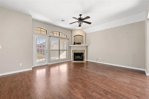 a view of an empty room with wooden floor fireplace and a window