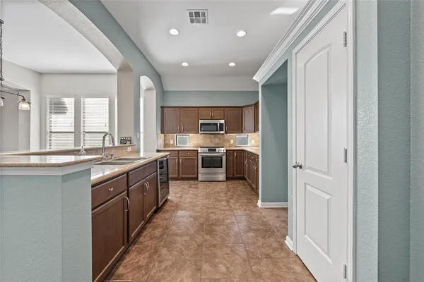 a large kitchen with stainless steel appliances granite countertop a large counter top and a sink