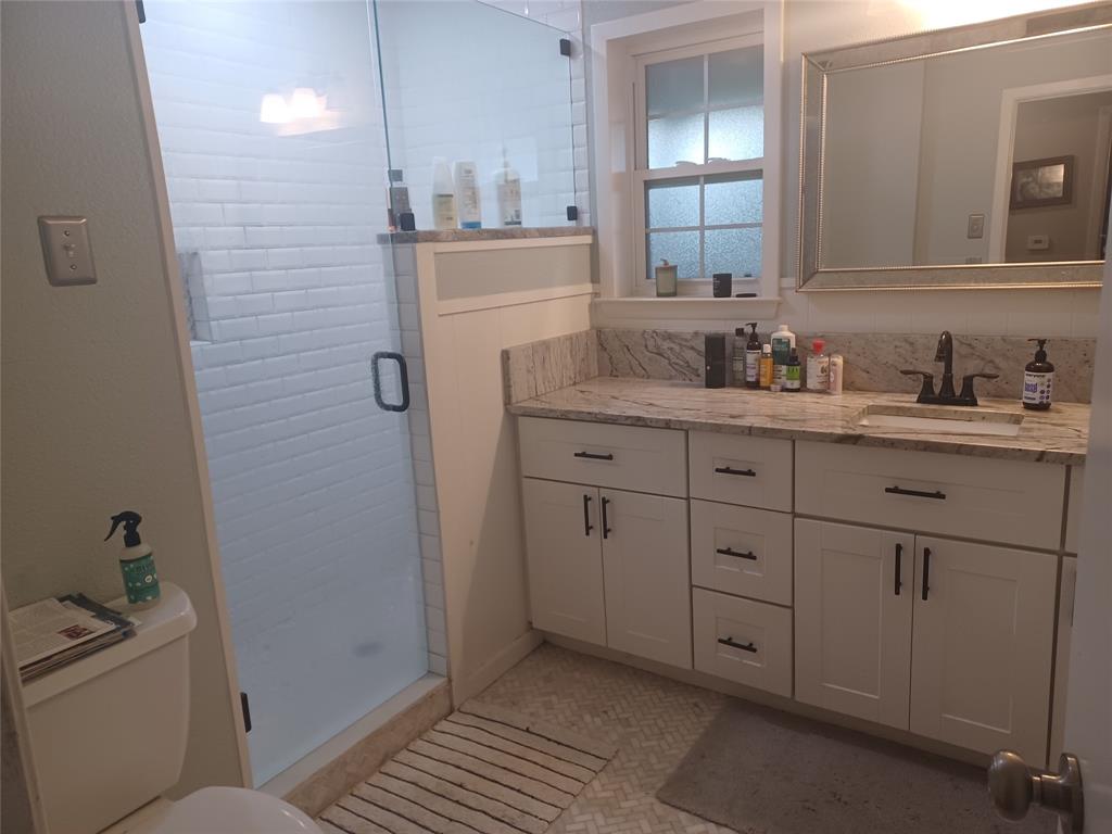415 Magnolia Street Denton, TX 76201 - Photo 16 of 23 a bathroom with a granite countertop sink a toilet and mirror