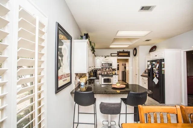 a kitchen with stainless steel appliances kitchen island granite countertop a refrigerator and a sink