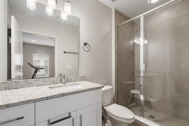 a bathroom with a granite countertop sink a toilet a mirror and shower