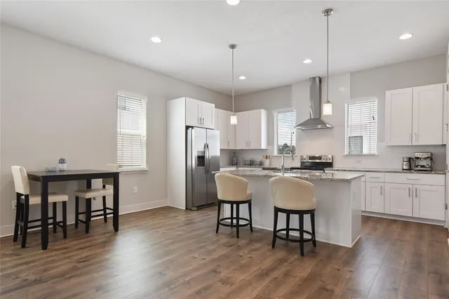 a kitchen with stainless steel appliances granite countertop a dining table chairs refrigerator sink and cabinets