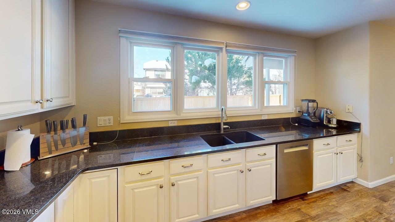 8958 South Forrest Drive Littleton, CO 80126 - Photo 16 of 27 a kitchen with granite countertop a sink and white cabinets