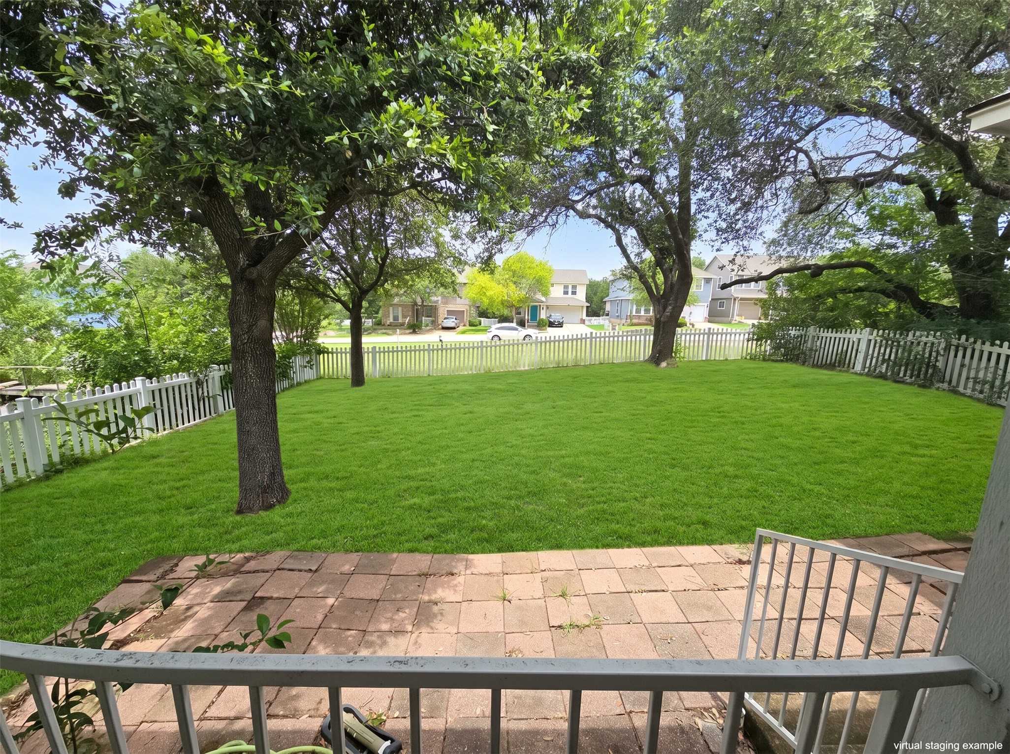 815 Bogart Road Cedar Park, TX 78613 - Photo 13 of 14 A pristine green lawn, framed by mature trees and a charming picket fence, offers ample outdoor space.