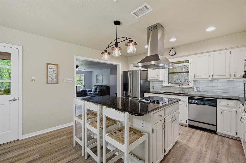 522 High Country Road Sherman, TX 75092 - Photo 10 of 38 a kitchen with stainless steel appliances granite countertop a stove top oven a sink dishwasher and white cabinets with wooden floor