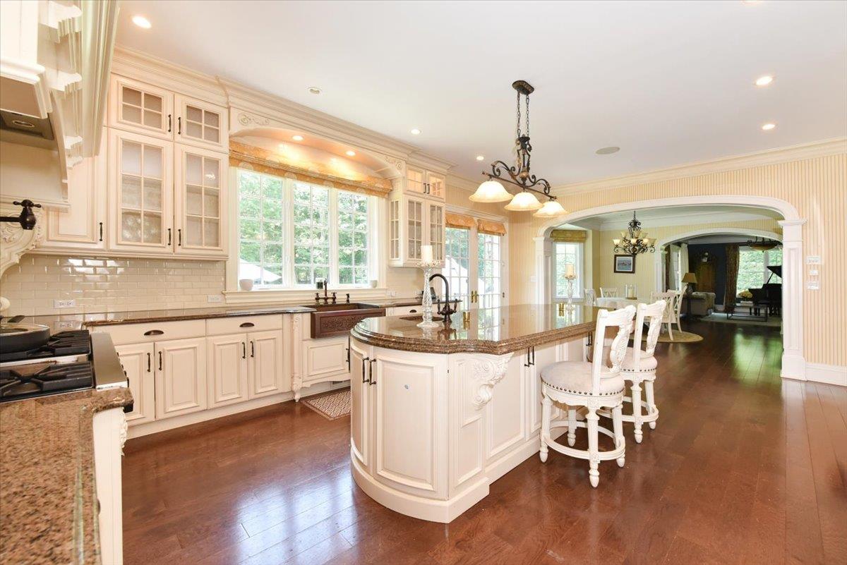 1616 Stewart Lane Syosset, NY 11791 - Photo 16 of 38 Kitchen with arched walkways, a chandelier, dark wood-style floors, ornamental molding, and dark stone counters
