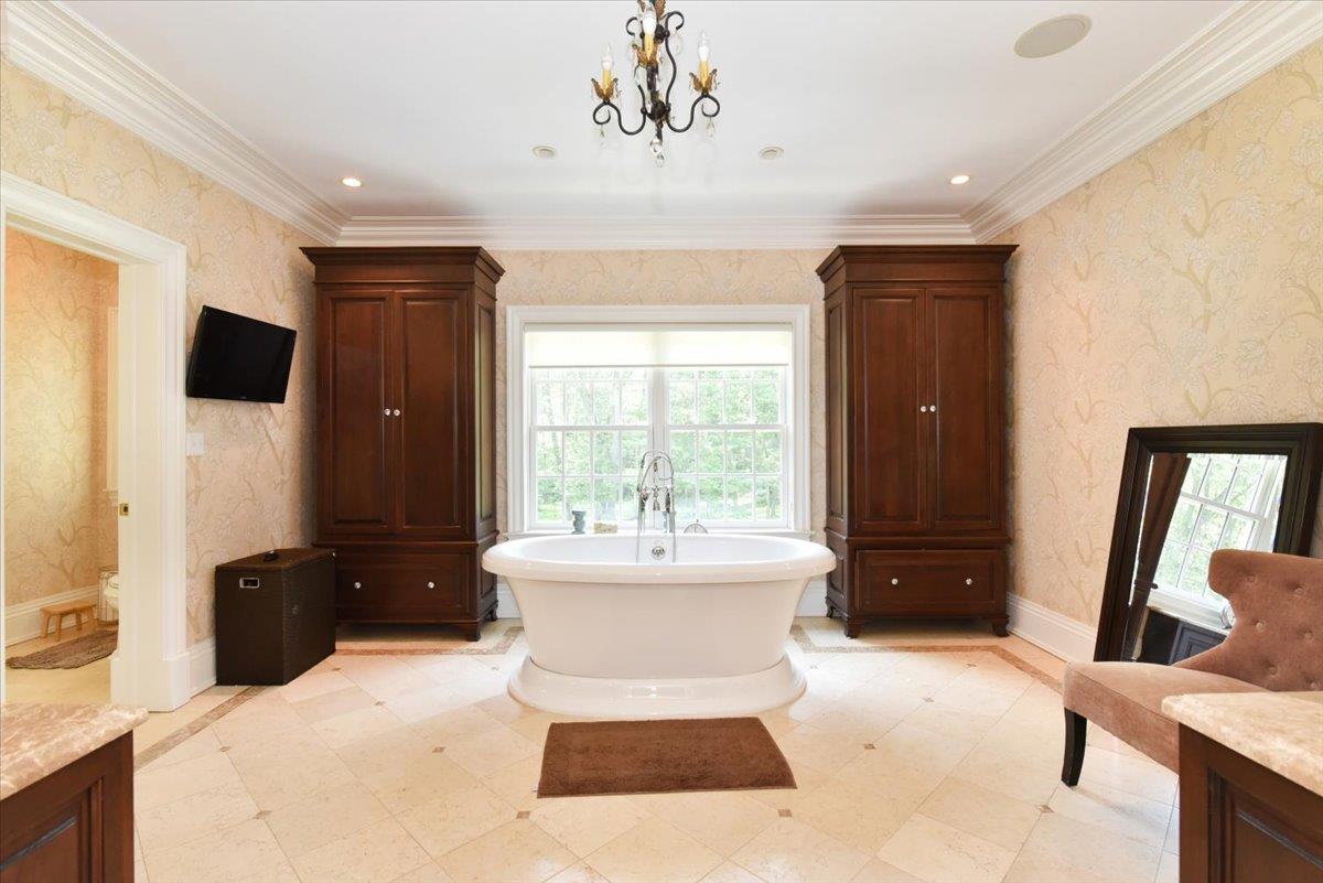 1616 Stewart Lane Syosset, NY 11791 - Photo 24 of 38 Bathroom with a soaking tub, wallpapered walls, vanity, crown molding, and a chandelier